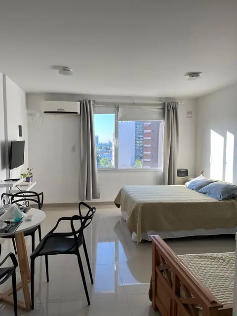 Departamento con comedor, cama y ventanal